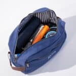 Blue canvas and leather dopp kit open showing toiletry items inside