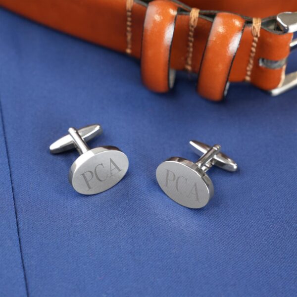 Silver oval cuff links paired with a brown belt and blue shirt