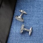 Silver oval cuff links paired with a blue shirt and black tie