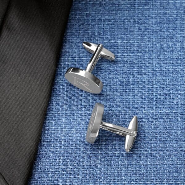 Silver oval cuff links paired with a blue shirt and black tie