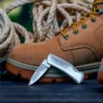 Stainless steel pocket knife next to a work boot