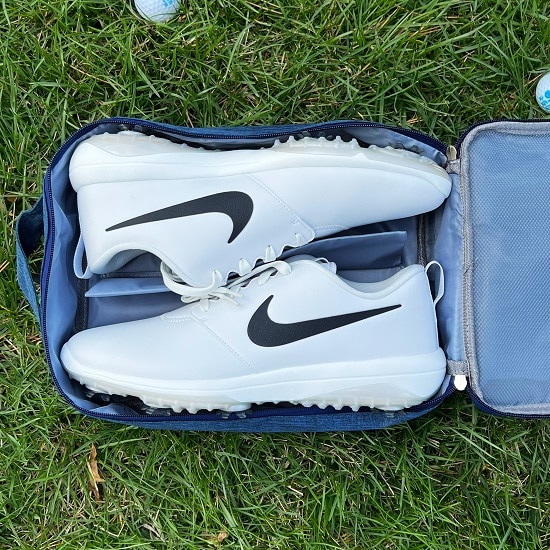 White Nike golf shoes in a blue golf shoe bag