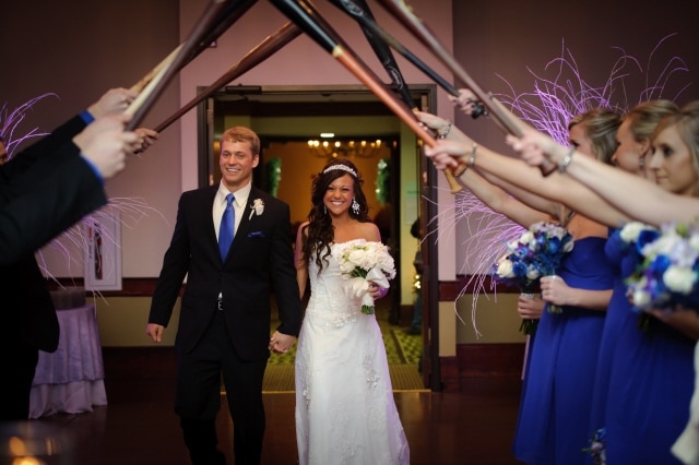 enter the wedding reception under a canopy of baseball bats