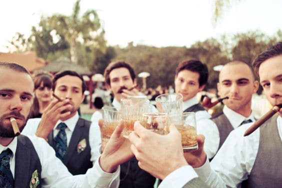 manly wedding ideas featuring groomsmen drinking whiskey and smoking cigars