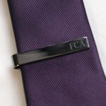 Black tie bar against a purple tie