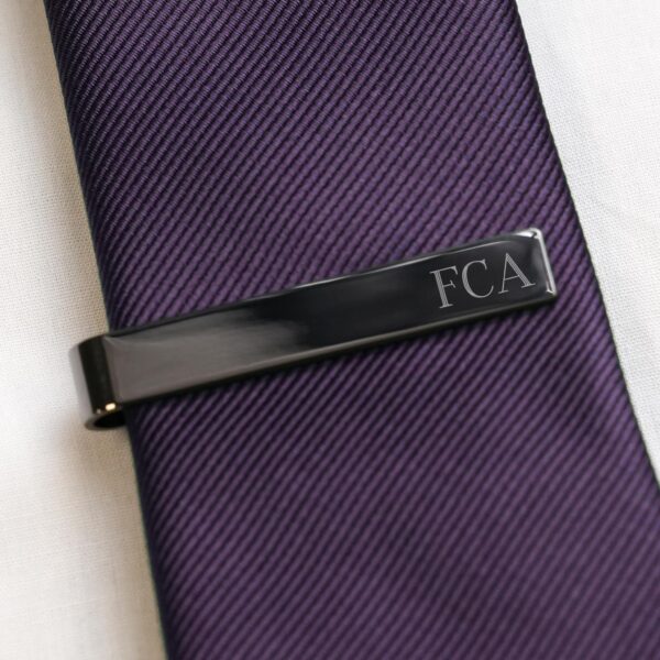 Black tie bar against a purple tie