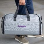 Grey suit saver bag with purple personalization thread being held by the carrying handles