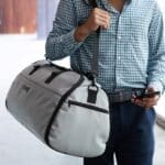 Grey Suit Saver v2 being worn over shoulder and used as a duffle bag