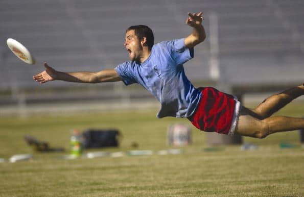 ultimate frisbee player diving for frisbee