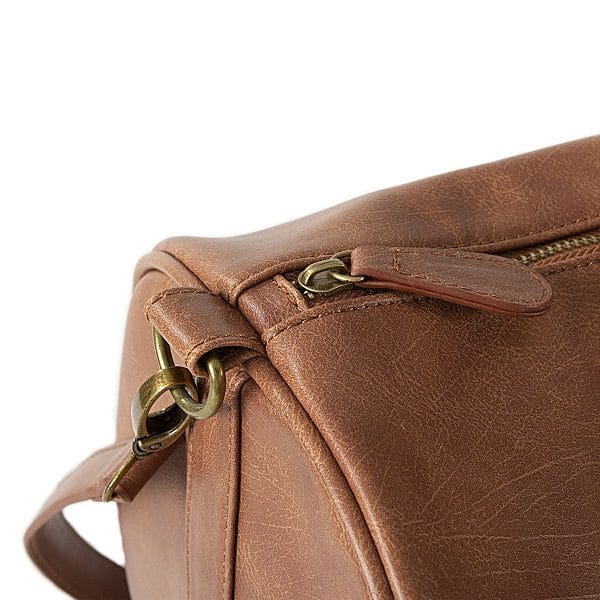 The Vegan Leather duffle bag features antique golden zippers.