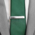 silver tie bar paired with a green tie and grey suit