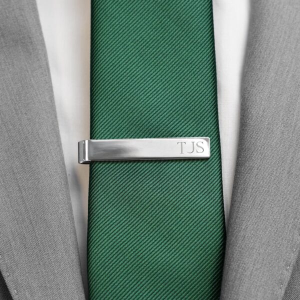 silver tie bar paired with a green tie and grey suit
