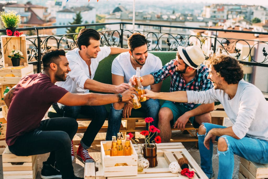 five groomsmen toasting at a party on the roof.