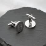 Round silver cuff links engraved with a single initial