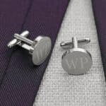 Round silver cufflinks pair with a blue tie