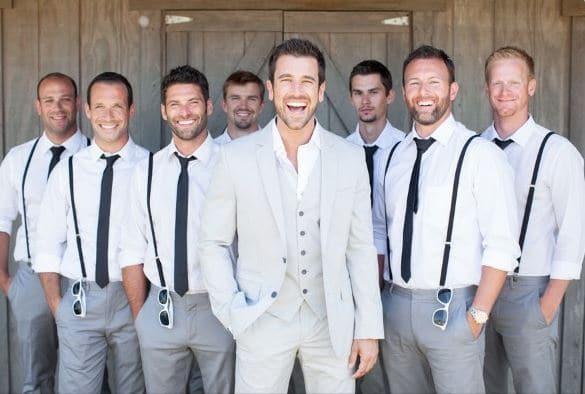 groomsmen wearing matching suspenders behind the groom who is front and center