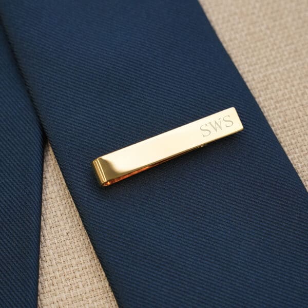 The gold tie clip is engraved with a name or initials for no extra cost