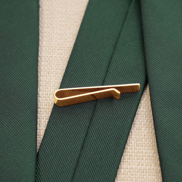 Gold tie clip paired with a green tie