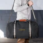 The groom holding a deluxe duffle bag as he prepares to travel to the bachelor party with his groomsmen
