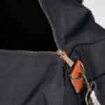A close-up of the zipper and vegan leather accents on the black nylon groomsmen duffle bag