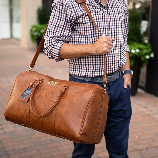 Man holding brown leather bag over his shoulder