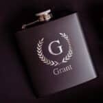 Black matte laser engraved flask shown with laurel wreath design
