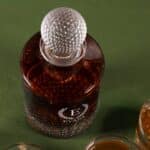 Golf decanter show full of whiskey with custom laurel wreath design laser engraved on front.