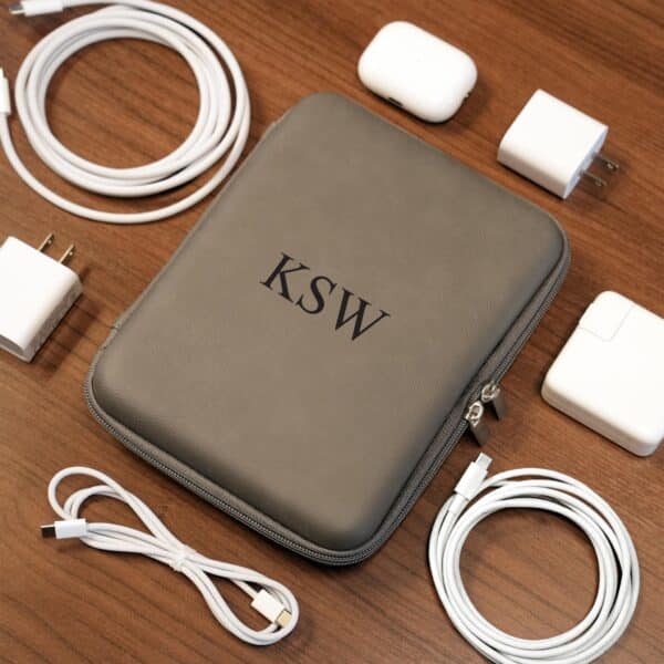 Grey cord case shown with an array of cords, chargers and tech gadgets that will all be stored neatly inside.
