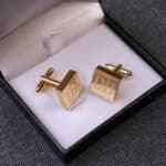 Gold square cuff links placed in black gift box