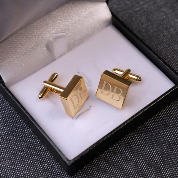 Gold square cuff links placed in black gift box