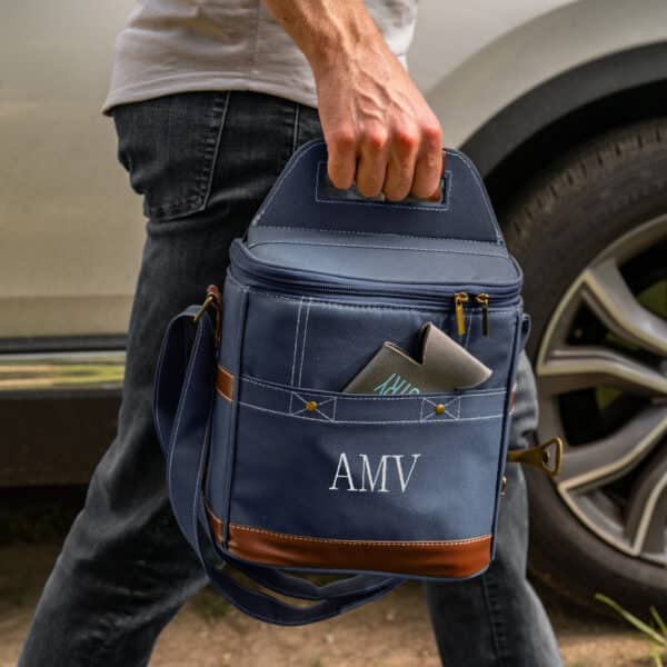 A man carrying a personal soft-sided blue cooler with custom embroidery of his initials.