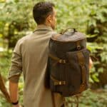 A man carrying a rugged camping backpack in the woods.