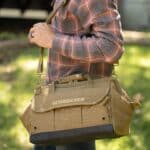 Man carrying green tool bag over his shoulder