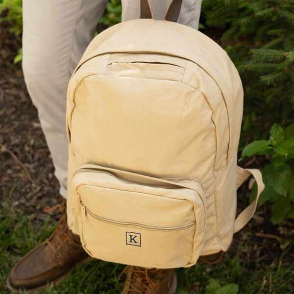 Khaki backpack personalized with a single initial inside a quare