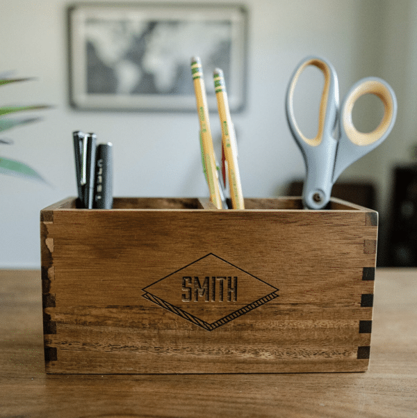 Engraved wooden desk caddy filled with pens, pencils and a pair of scissors