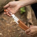 Elk Ridge Fixed Blade Knife showing being put in the accompanying brown leather sheath.