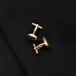 Gold round cufflinks set against a black suit