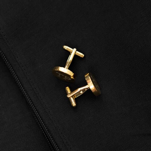 Gold round cufflinks set against a black suit