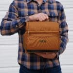 A man in a plaid shirt holding his brown personalized lunch cooler