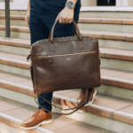 A man carries his engraved brown leather briefcase down a flight of stairs