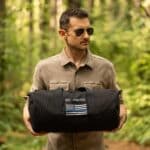 Police officer holding his custom tactical bag in the woods