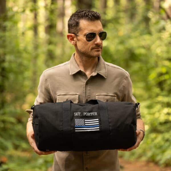 Police officer holding his custom tactical bag in the woods