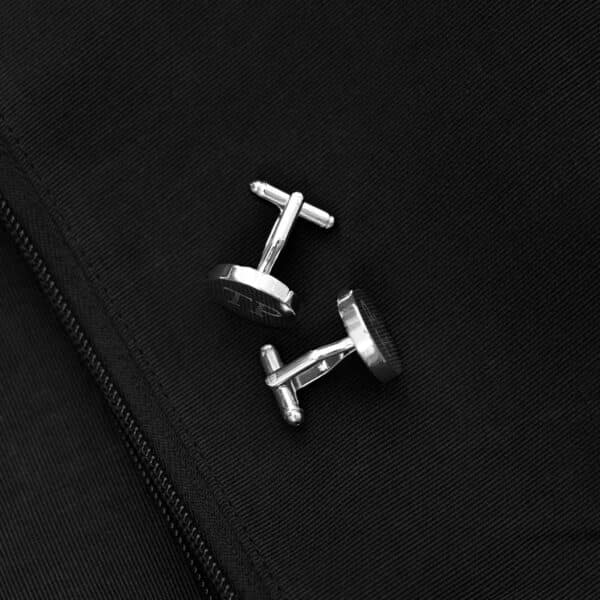 Silver round cufflinks set against a black suit