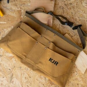 Personalized tool belt laying flat in a woodshop setting