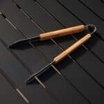 Grill tongs open on a backyard patio table