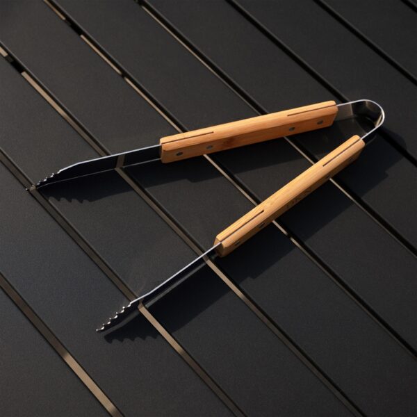 Grill tongs open on a backyard patio table